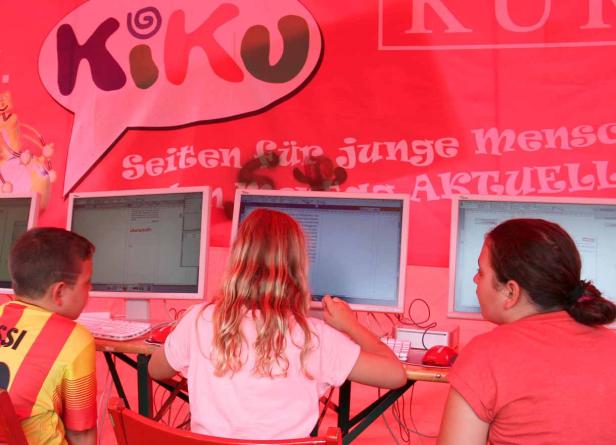 Kinder sitzen an Computern unter einem „KiKo“-Banner.