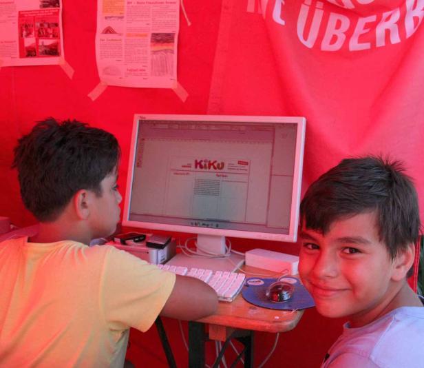 Zwei Jungen sitzen vor einem Computer mit der KiKu-Webseite.