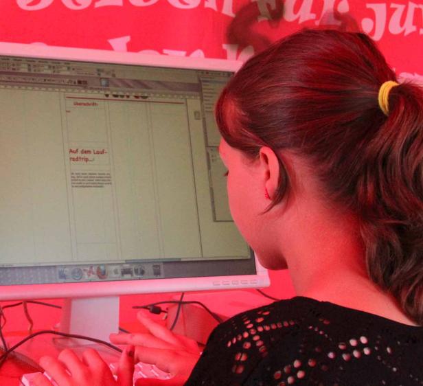 Eine Frau arbeitet an einem Computer; auf dem Bildschirm ist Text zu sehen.