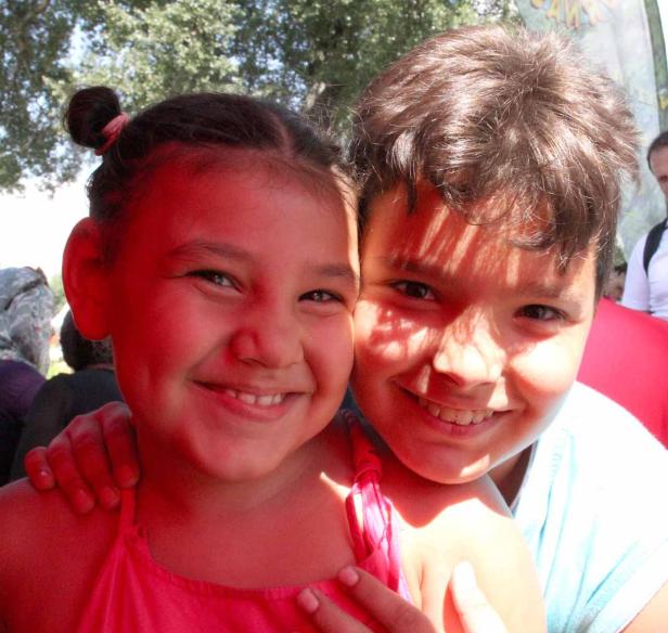 Ein lächelndes Mädchen und ein lächelnder Junge umarmen sich.