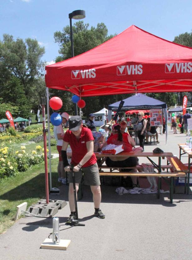 Eine Frau pumpt eine kleine Rakete auf einem Stand der VHS auf einem öffentlichen Platz auf.