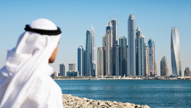 Ein Mann in traditioneller Kleidung blickt auf die Skyline von Dubai.