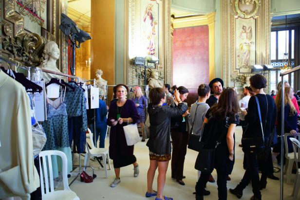 Blick hinter die Kulissen einer Modenschau mit Models und Kleiderständern.