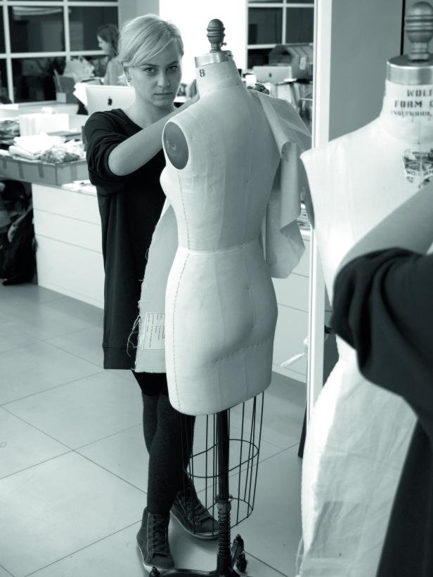 Eine Frau drapiert Stoff auf einer Schneiderpuppe.