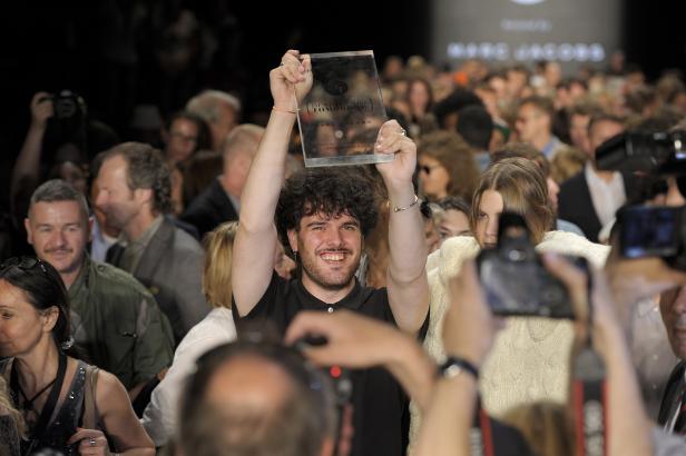 Ein Mann hält eine Auszeichnung von Marc Jacobs bei der Mercedes-Benz Fashion Week 2018 in die Höhe.