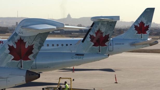 Zwei Flugzeuge von Air Canada mit dem roten Ahornblatt auf dem Heck stehen auf einem Flugfeld.