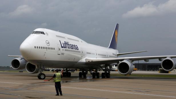 Ein Lufthansa-Jumbo-Jet wird auf dem Rollfeld von einem Mitarbeiter eingewiesen.