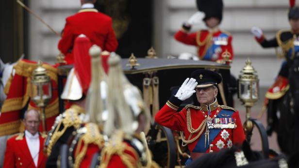 Prinz Philip in roter Uniform salutiert aus einer Kutsche.