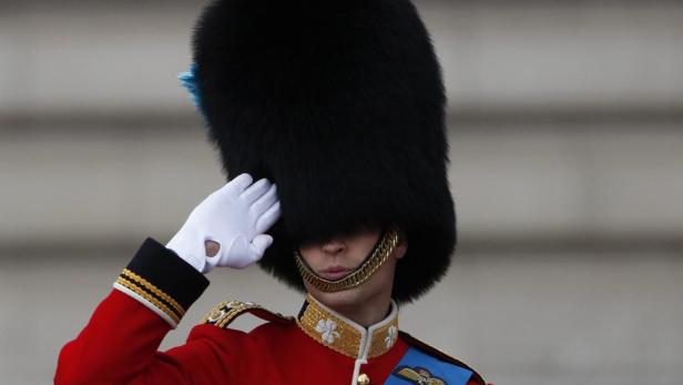 Ein britischer Gardesoldat in roter Uniform und Bärenfellmütze salutiert.