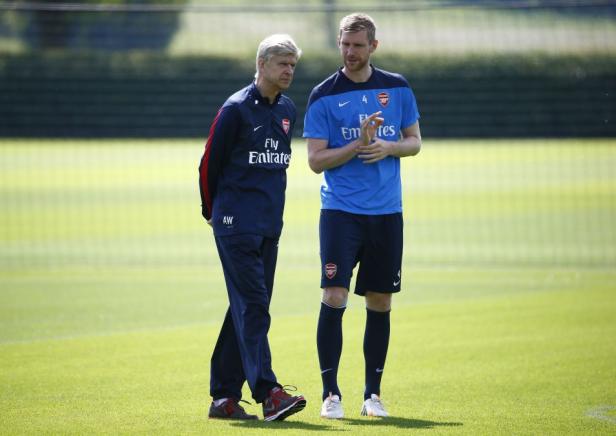 Arsène Wenger und Per Mertesacker stehen auf einem grünen Rasen.