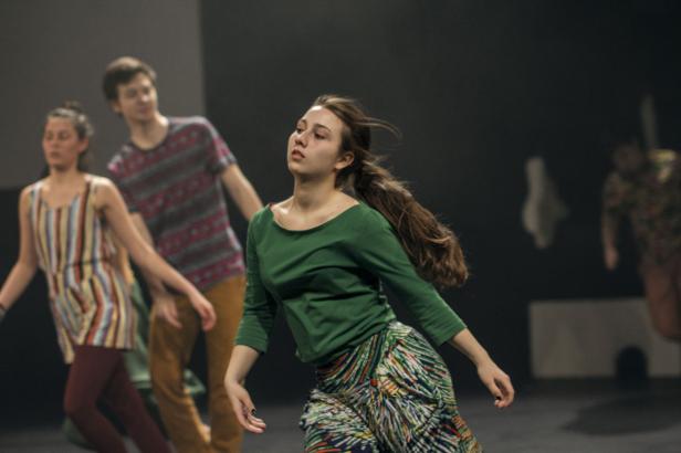 Eine junge Frau tanzt mit anderen Tänzern auf einer Bühne.