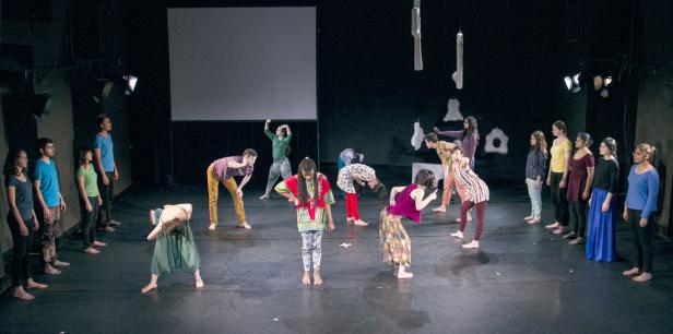 Eine Gruppe von Tänzern führt eine Performance auf einer Bühne auf.