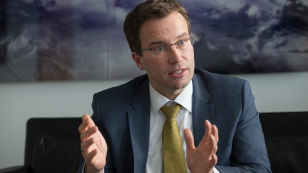 Ein Mann mit Brille und Anzug gestikuliert während eines Gesprächs.