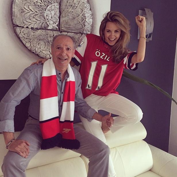 Ein Mann mit Arsenal-Schal und eine Frau im Özil-Trikot posieren auf einem Sofa.