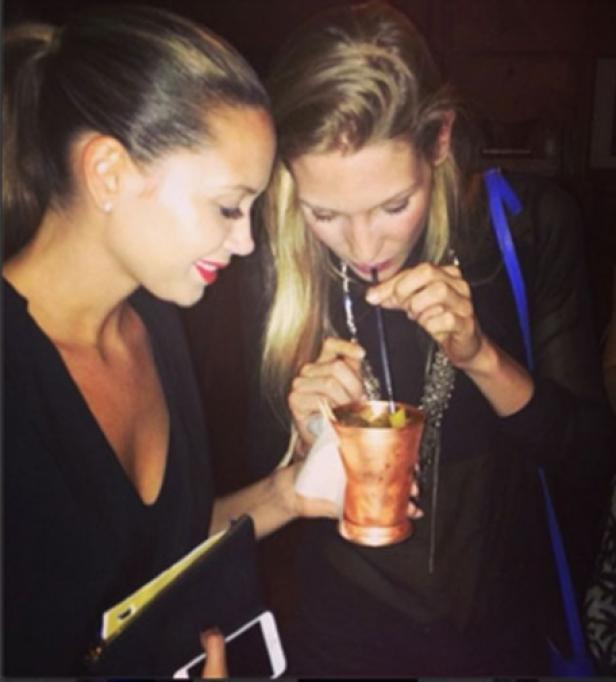 Zwei Frauen teilen sich einen Drink aus einem Kupferbecher mit Strohhalmen.