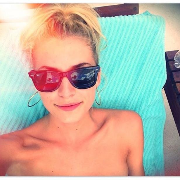 Eine Frau mit Sonnenbrille liegt auf einem Liegestuhl mit blauem Handtuch.