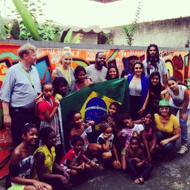 Eine Gruppe von Menschen hält eine brasilianische Flagge vor einer Graffiti-Wand.
