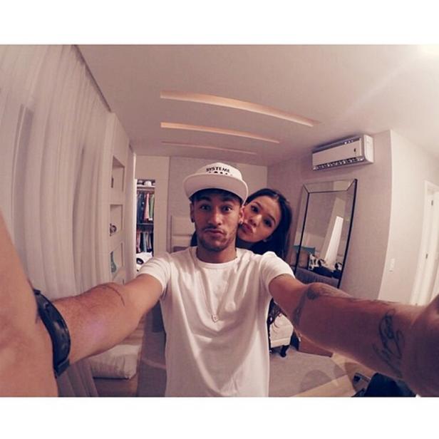 Neymar macht ein Selfie mit einer Frau in einem Zimmer.