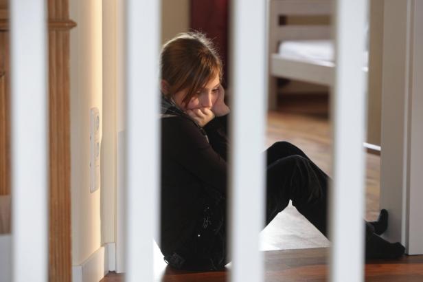 depression Eine junge Frau sitzt nachdenklich auf dem Boden.