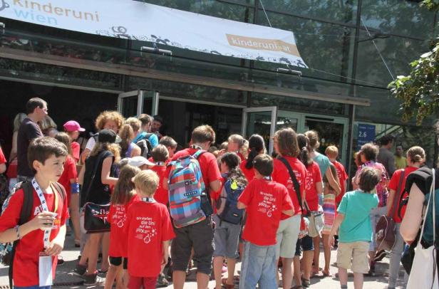 Eine Gruppe Kinder steht vor dem Eingang der Kinderuni Wien.