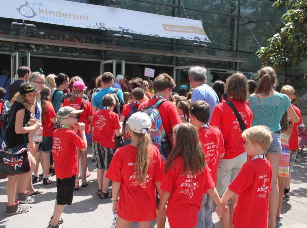 Eine Gruppe Kinder in roten T-Shirts vor dem Eingang der Kinderuni Wien.