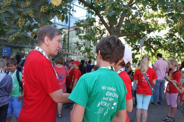 Eine Gruppe von Kindern und Erwachsenen steht vor einem Gebäude.