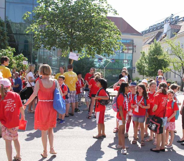 Eine Gruppe Kinder in roten T-Shirts steht im Freien vor einem Gebäude.