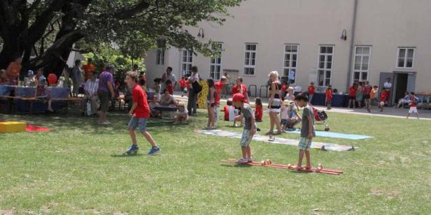 Kinder spielen und feiern auf einer Wiese bei einem Sommerfest.