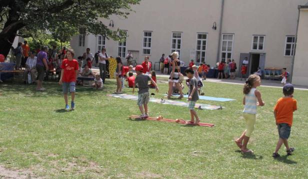 Eine Gruppe Kinder spielt und vergnügt sich auf einer Wiese.