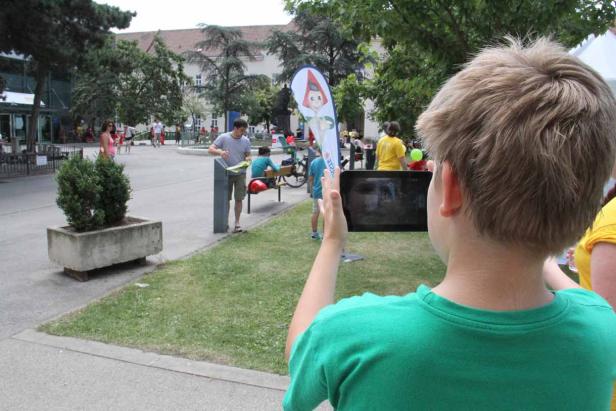 Ein Junge macht mit einem Tablet ein Foto in einem Park.