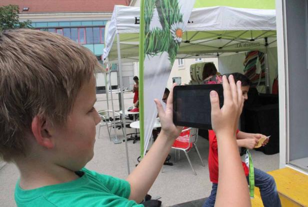 Ein Junge macht mit einem Tablet ein Foto von einem Stand.