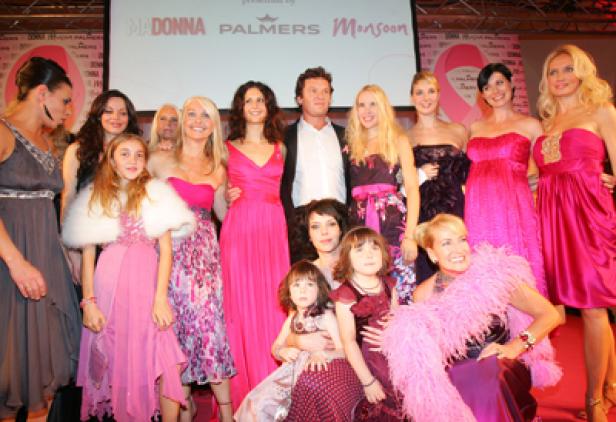 Eine Gruppe von Frauen und Mädchen posiert auf einer Bühne für eine Veranstaltung von Madonna, Palmers und Monsoon.