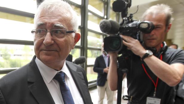 Ein älterer Mann im Anzug wird von einem Kameramann gefilmt.