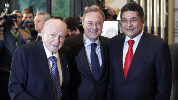 Drei Männer in Anzügen posieren für ein Foto.