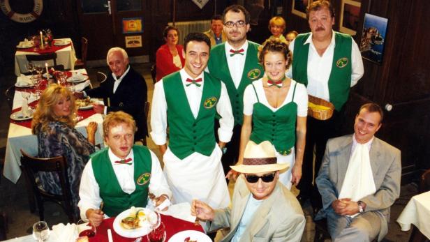 Eine Gruppe von Menschen sitzt und steht in einem Restaurant.