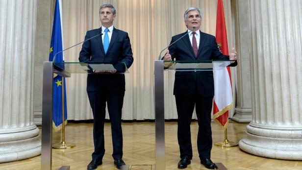 Zwei Männer stehen an Rednerpulten vor der Europa- und Österreichflagge.