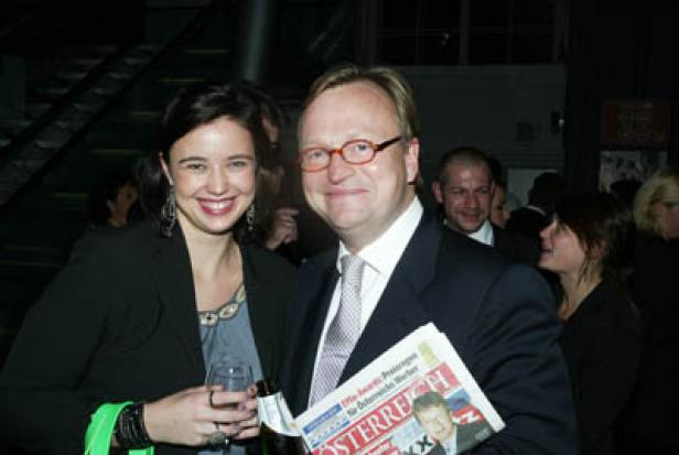 Eine Frau mit einem Weinglas und ein Mann mit einer Zeitung der Marke „Österreich“ posieren für ein Foto.