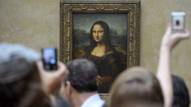 Besucher fotografieren Leonardo da Vincis „Mona Lisa“ im Louvre in Paris.