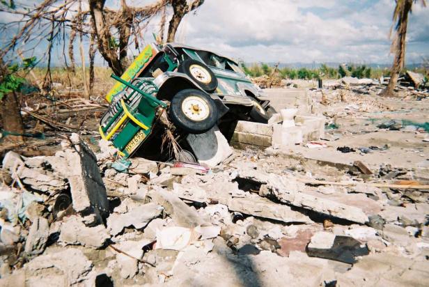Ein durch einen Tsunami zerstörtes Jeepney liegt auf einem Trümmerhaufen.