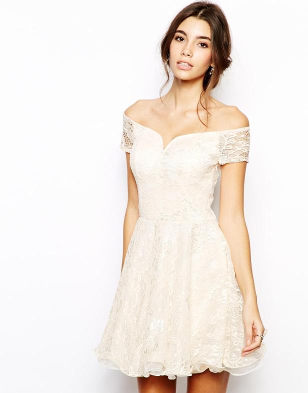 Eine junge Frau trägt ein schulterfreies, kurzes Kleid aus Spitze.