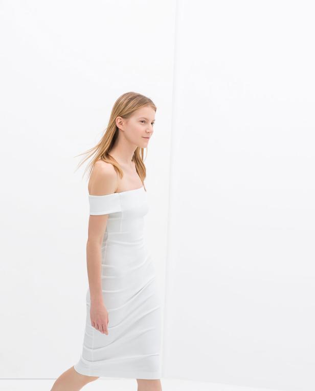 Eine Frau mit blonden Haaren trägt ein weißes, schulterfreies Kleid.