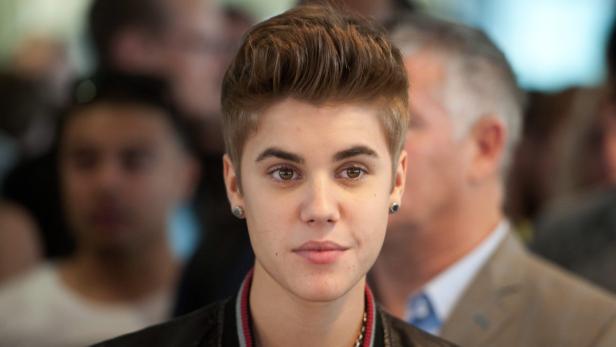 Ein Porträt von Justin Bieber mit Ohrringen vor einer unscharfen Menschenmenge.