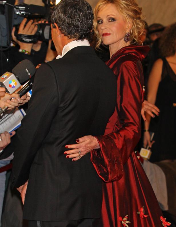 Jane Fonda in rotem Kleid mit Blumenmuster und ein Mann im Anzug auf dem roten Teppich.