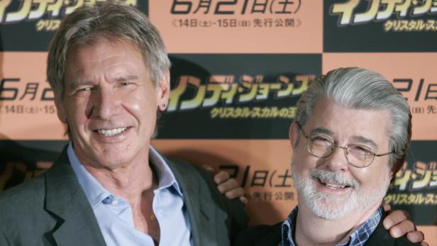 Harrison Ford und George Lucas posieren vor einem Werbeplakat für „Indiana Jones und das Königreich des Kristallschädels“.