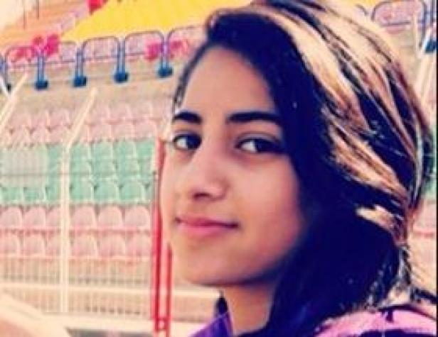 Eine junge Frau mit dunklen Haaren lächelt in die Kamera.