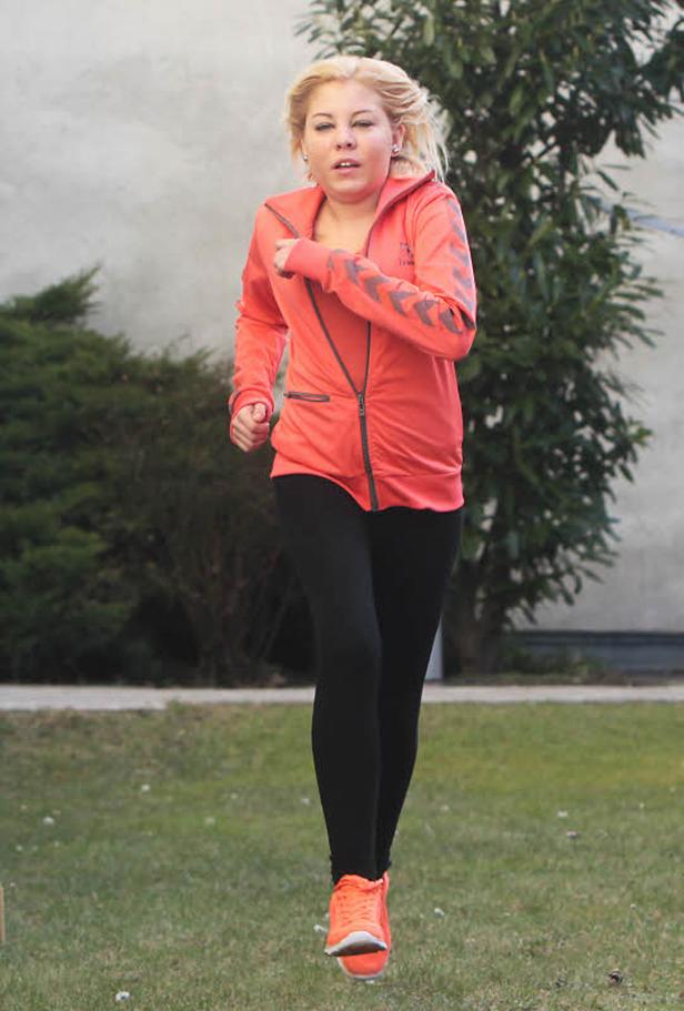 Eine Frau joggt in Sportkleidung über eine Wiese.