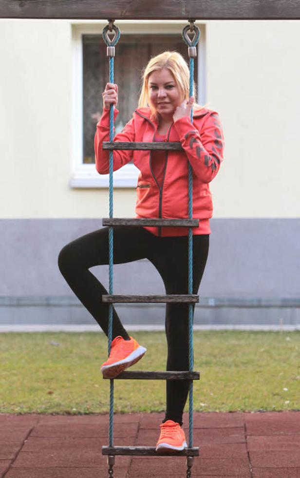 Eine Frau klettert auf einer Strickleiter auf einem Spielplatz.
