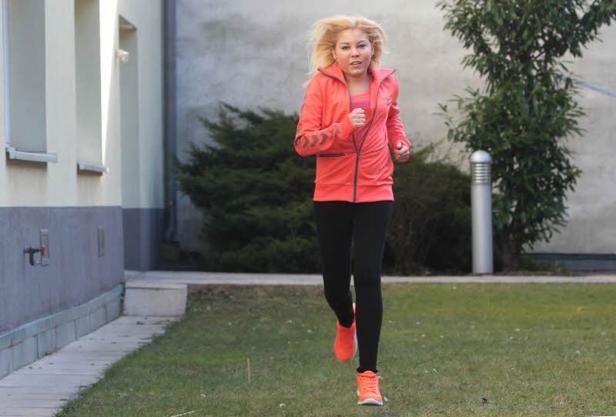 Eine junge Frau joggt in Sportkleidung auf einer Rasenfläche.