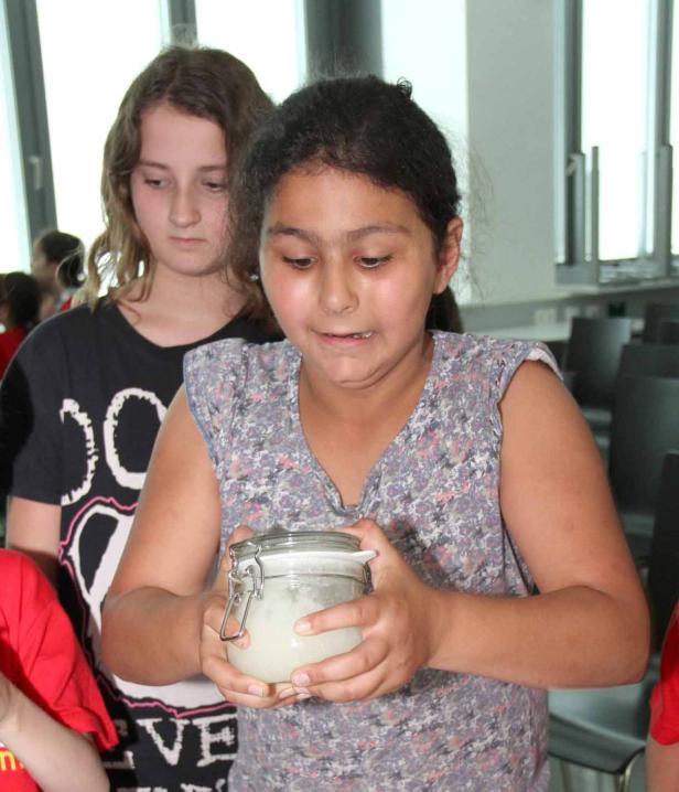 Ein Mädchen hält ein Glas mit einer weißen Substanz in den Händen.