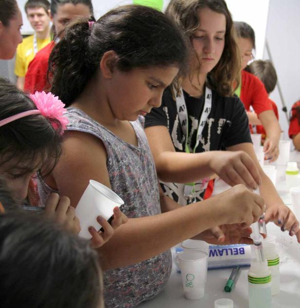 Mehrere Kinder experimentieren mit Spritzen und Bechern in einem Labor.